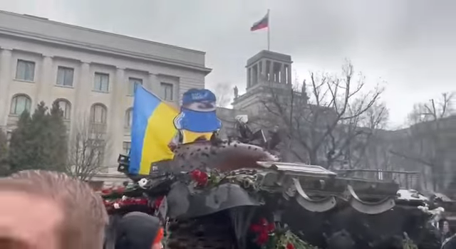 Люди в Берлине несут цветы к российскому танку