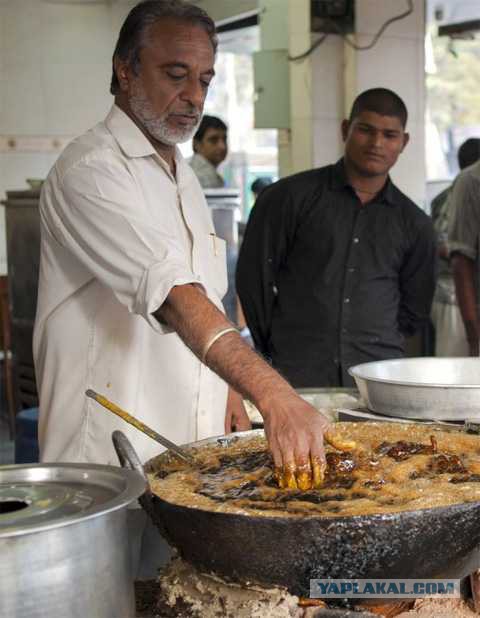 Индийский повар окунает руки в кипящее масло