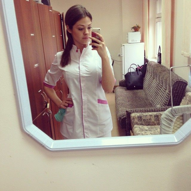 медицинский работник примеряет униформу перед зеркалом