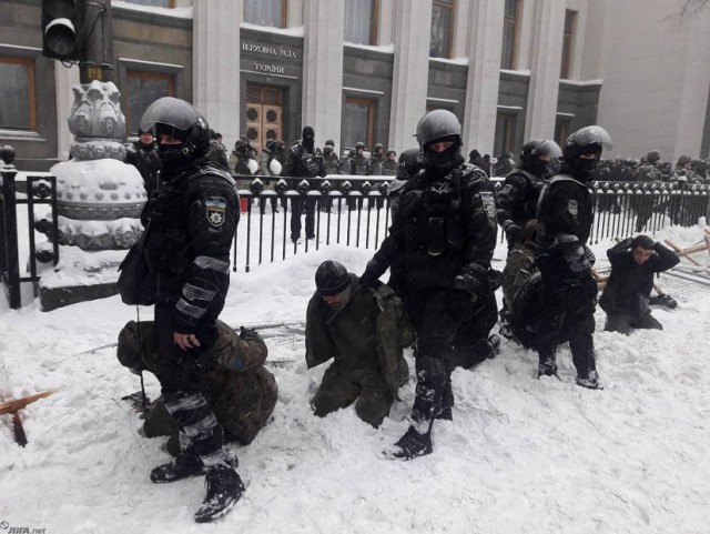 Целая группа полицейских собралась, чтобы придумать повод для задержания одного человека с плакатом по поводу пенсионной реформы